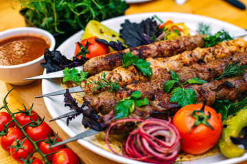 assorted kebabs with grilled vegetables and spicy sauce on a decorated table