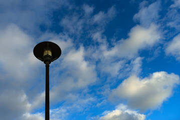 Farola recortándose sobre un cielo azul vestido de nubes.