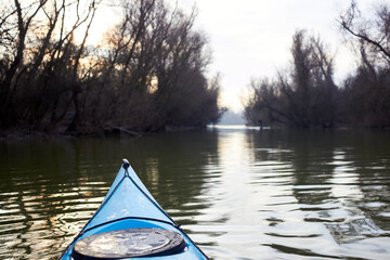 Fototapeta premium Bow (prow) of blue kayak in winter or early spring river. Winter kayaking