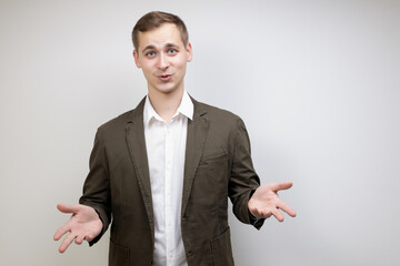 Handsome male businessman spread his hands to the sides gesturing during discussion on gray background with copy space