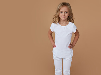 Obraz premium Front portrait of pretty little cute girl with wavy hair, dressed in white clothes. Fashion photo. Horizontal view.