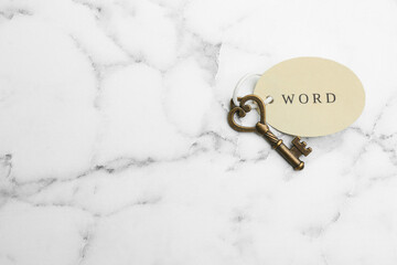 Vintage key with tag on white marble table, top view and space for text. Keyword concept