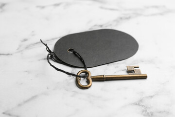 Fototapeta na wymiar Vintage key with blank tag on white marble table. Keyword concept