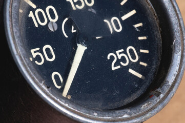 Old rusty round industrial pressure gauge with numbers on a black dial
