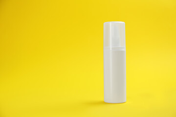 Bottle with insect repellent spray on yellow background, space for text