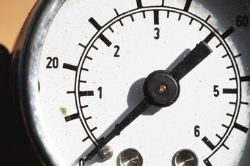Old rusty round industrial pressure gauge with numbers on a white dial.
