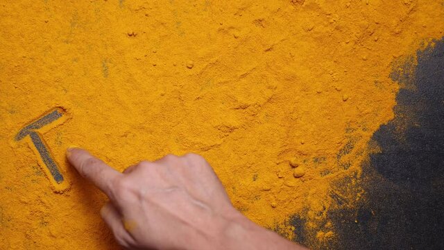 Indian spices turmeric powder hand writing Turmeric in curcuma longa black background, Kerala India Sri Lanka Indian curry masala 4K slow motion video footage, antiseptic antiviral Ayurvedic medicine.