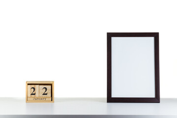 Wooden calendar 22 January with frame for photo on white table and background