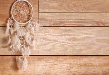 Beautiful dream catcher hanging on wooden wall, space for text