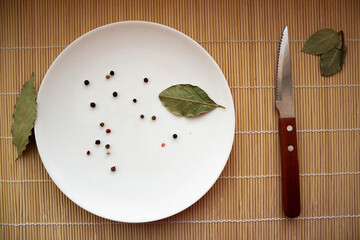 pepper, steak knife, and a bay leaf on a wood rug