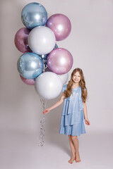 Fototapeta na wymiar birthday concept - happy girl posing with pastel air balloons over white background.