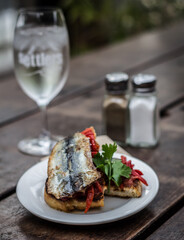 Sardine with capsicum onion and green leaves on crunchy bread and white dish