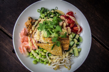 Nourish Bowl with tempeh, brown rice, cucumber, edamame beans, tomato, bean sprouts, coriander in white dish