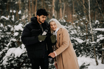 couple in winter forest drinking tea