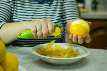 The process of making limoncello lemon liqueur at home. The woman removes the zest from the lemons.