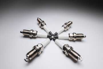 Six new ICE spark plugs on a gray background in contrasting light
