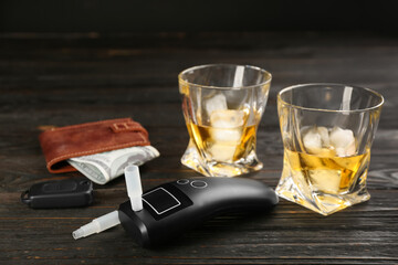 Modern breathalyzer, car key, alcohol and wallet on dark wooden background