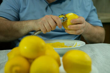 The process of making limoncello lemon liqueur at home. The man removes the zest from the lemons.