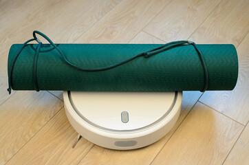 A robot vacuum cleaner carries a yoga mat.