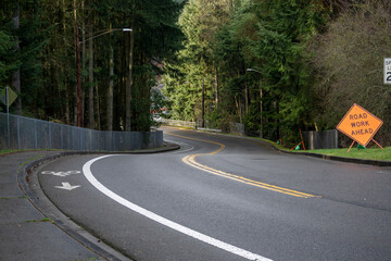 Curving road with bicycle lane and road work sign