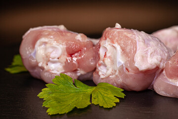 Fresh chicken leg with greens on a black background