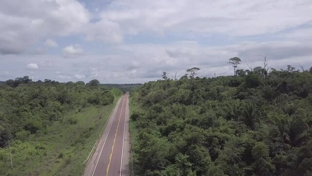 Aerial drone view of Transamazonica highway BR 230 road new asphalt and beautiful trees in the amazon rainforest on sunny day. Concept of nature, environment, ecology, transport, deforestation, co2.