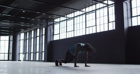 African american woman doing jumping exercises in an empty urban building