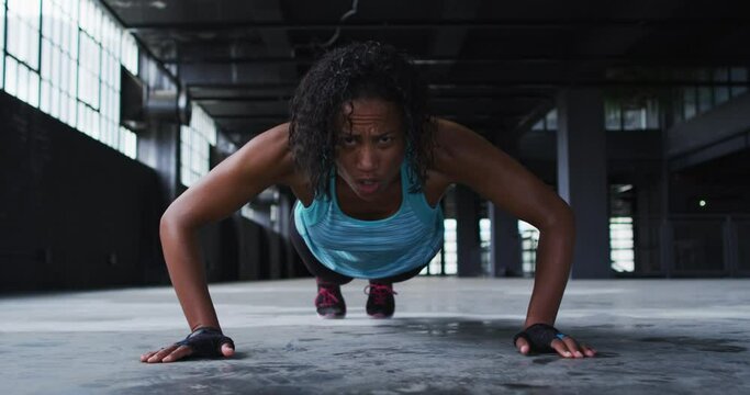 African american woman doing push ups in an empty urban building