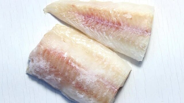 Frozen pollock fillet on a white background. The view from the top.