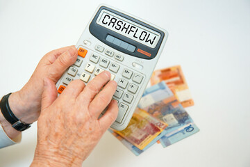 An elderly woman holds a calculator and calculator inscription - CASHFLOW.