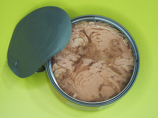 Canned tuna fillet with natural liquid in a metal jar on a bright background, flat layout. Tinned healthy seafood with omega, family scombridae, for long-term storage