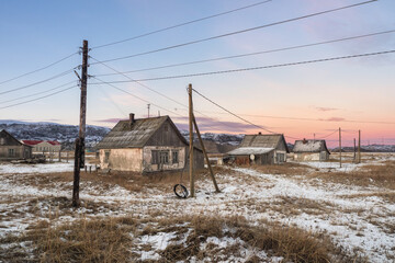 Abandoned houses against the Arctic sky. Old authentic village of Teriberka. Kola Peninsula.