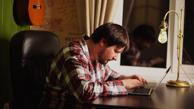 a man in red plaid pajamas worked late at the computer and fell asleep.