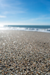 Close up of sand grains on a beach with blurred coastline and horizon in background