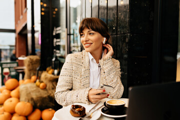 Image of pretty business woman working on laptop on street cafe, smart lady smiling and looking away 