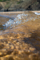 Waves breaking on the coast, spray, white water and light reflected on the surface of the water