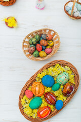 Fototapeta na wymiar Multi-colored Easter eggs in a basket on a white wooden background