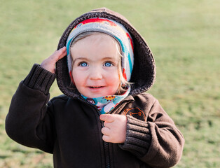 Toddler girl on grassy field with ahoy gesture