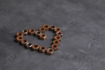 Heart made of small rusty nuts. Machine parts. Items on a dark background.