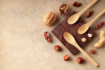 Vegetarianism concept. Wooden spoons for hazelnuts, peanuts, walnuts on a light background. Homemade raw organic product. Top view, flat. Copy space.