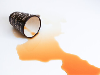 tilt overed coffee mug spilled and flowing coffee is  isolated on white background