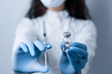 Doctor holding coronavirus vaccine. Covid-19 Vaccination. Stop quarantine. Close-up suringe and medication