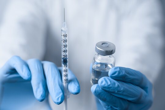 Doctor holding coronavirus vaccine. Covid-19 Vaccination. Stop quarantine. Close-up suringe and medication