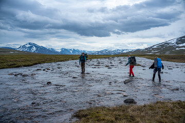 Groupe of Hiking Friends wading across the river By Team Working