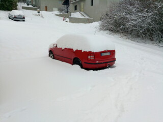 Red car surrounded by snow and with the top of the vehicle completely covered with snow, in winter, in Vetraz-Monthoux in Haute-Savoie