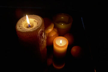 candles light up tangerines and persimmons in dark
