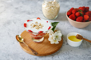 Oatmeal dessert with fresh strawberries. Healthy breakfast of strawberry parfait with fresh fruit and yogurt on a gray table. Panna Cotta. Correct, natural nutrition. Space for text. Still life