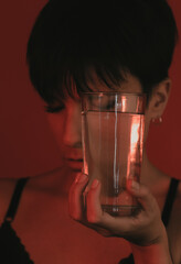Portrait of a woman with her eyes closed holding a glass of water in studio