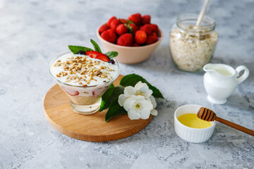 Oatmeal dessert with fresh strawberries. Healthy breakfast of strawberry parfait with fresh fruit and yogurt on a gray table. Panna Cotta. Correct, natural nutrition. Space for text. Still life