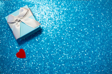 Banner. Velentin Day, blue gift box with gray bow and red heart on a light blue background with sparkles. Place for the text. Holiday concept, congratulations